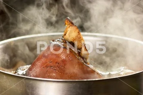 Roasted pork boiling in saucepan. Stock Photos