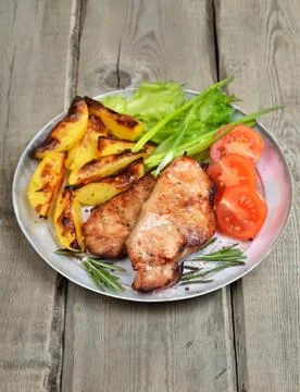 Roasted pork chop with vegetables on rustic table Stock Photos