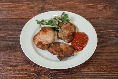 Roasted pork neck on a plate. Appetizing dish on the wooden brown table. Stock Photos