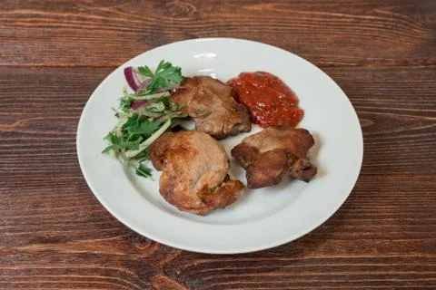 Roasted pork neck on a plate. Appetizing dish on the wooden brown table. Stock Photos