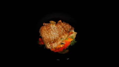 Roasted pork with vegetables in the spinning table isolated on black background Vidéo 104722230