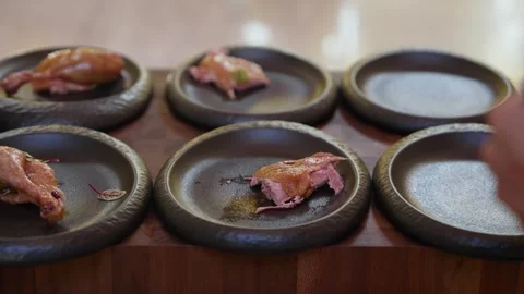Roasted poultry pieces on rustic dark plates arranged on wooden table with chef Vídeo Stock 340360078