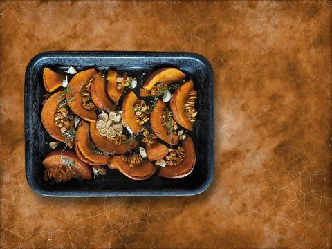 Roasted pumpkin and garlic with thyme on baking pan. Stock Photos
