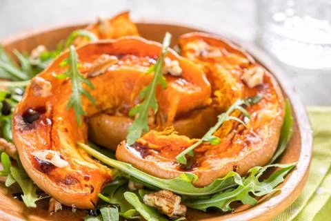 Roasted pumpkin with pecan nuts and arugula. Stock Photos