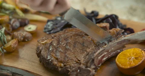 Roasted rack of pork cut with a big kitchen knife, with thyme, roasted potatoes, Stock Footage 199460197