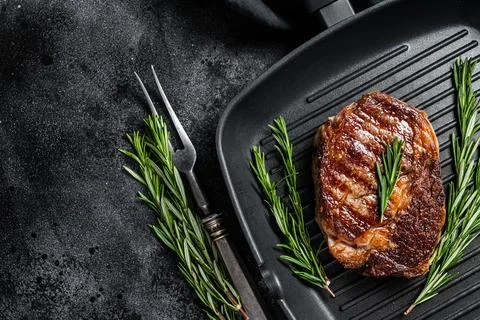 Roasted rib eye steak, ribeye beef meat in a grill pan. Black background. top Stock Photos