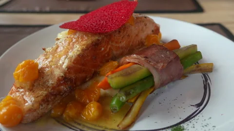 Roasted salmon fillet served over green asparagus with cherry tomatoes and Stock Footage 332484588