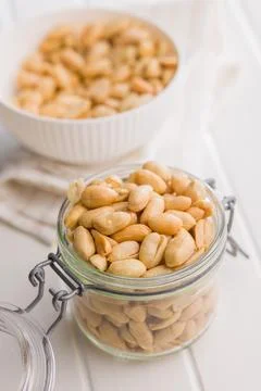 Roasted salted peanuts in jar on white table. Stock Photos