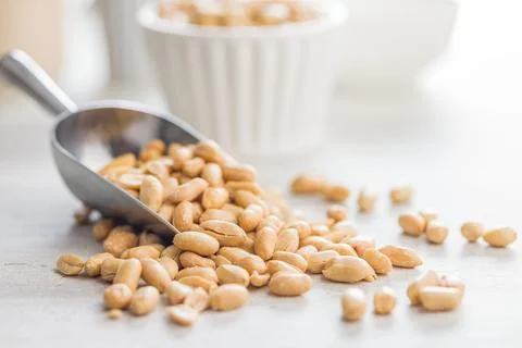 Roasted salted peanuts in scoop on kitchen table Foto stock
