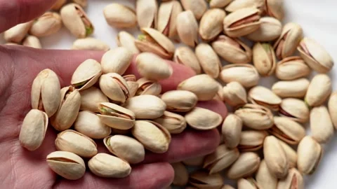 Roasted salted pistachios rolling off an open human hand Stock Footage 334872509