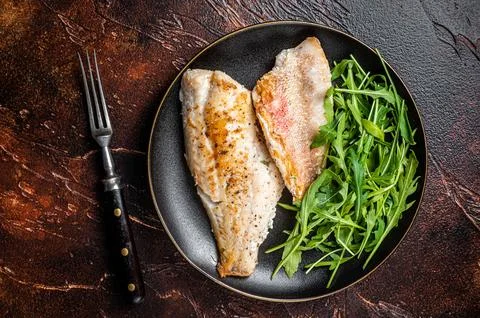 Roasted Snapper, sea red perch fillet on a plate with salad. Dark background Stock Photos