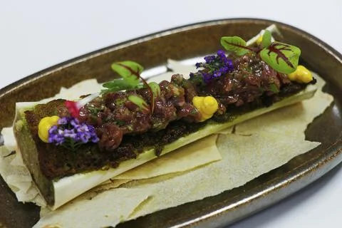 Roasted split veal bone marrow with beef tartare on Stock Photos