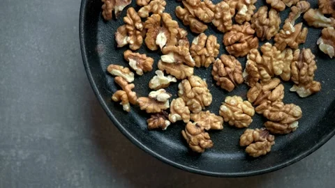 Roasted tasty walnuts in black spinning pan against concrete background. Stock Footage 222200728