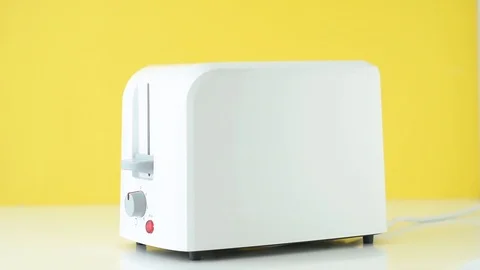 Roasted toast bread popping up from white toaster on a yellow background, slo Stock Footage 119248270