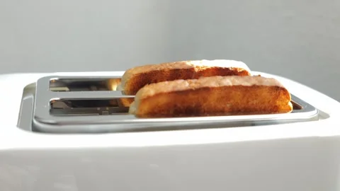 Roasted toast bread popping up from a white modern toaster in a kitchen. Stock Footage 329757653