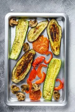 Roasted vegetables on a baking pan. White background. Top view Stock Photos