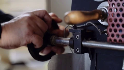The roaster opens the roaster door to unload coffee beans into the drum for Stock Footage 120165103
