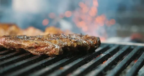 Roasting beef steak with grill, cooking on coals and fire. Sparkles and flames Video stock 135796278
