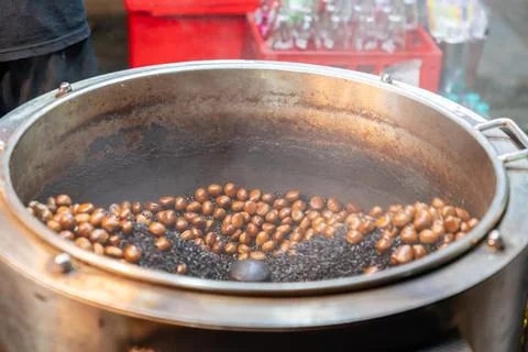 Roasting chestnuts in a rotating drum. Stock Photos