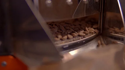 Roasting coffee .Coffee pours through the chute in a paper bag from the VAT Stock Footage 99750357