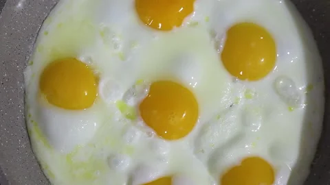 Roasting eggs in a frying pan. Scrambled eggs are fried in a frying pan, there Stock Footage 146905874