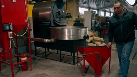 At a roasting factory, a worker uses a machine to distribute ready-made coffee Vídeo Stock 277808465