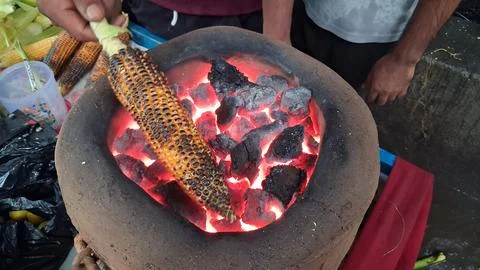 Roasting fresh raw corn over a coal fire Stock Photos