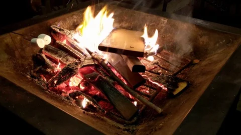 Roasting marshmallow around a firepit in the backyard at night with friends Stock Footage 127632899