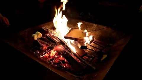 Roasting marshmallow around a firepit in the backyard in slow motion Stock Footage 127634362