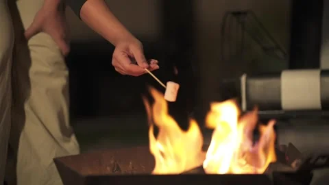 Roasting marshmallow over an outdoor fire pit during an evening gathering Stock Footage 339069446