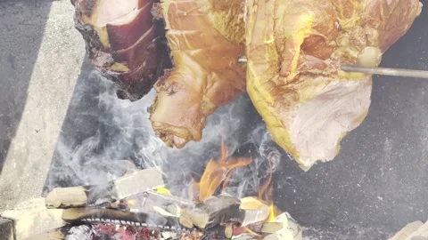 Roasting meat on open fire with flames and smoke, large cuts on metal spit Stock-Footage 332567388