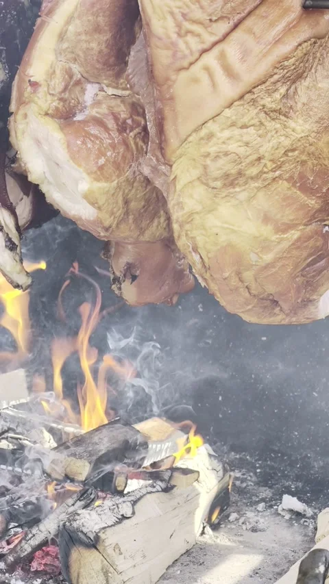 Roasting meat on open fire with flames and smoke, large cuts on metal spit Video stock 332567461