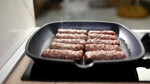Roasting meat. Smooth Camera zoom into a frying pan with smoky sausages. Vídeo Stock 244207598
