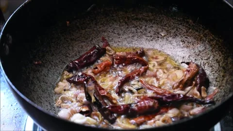 Roasting onions, dried red chilli and curry leaves in oil to make tadka. Tadk Stock Footage 138517223
