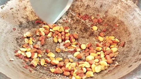 Roasting peanuts with salt in an iron wok with a spatula. Video stock 342400512