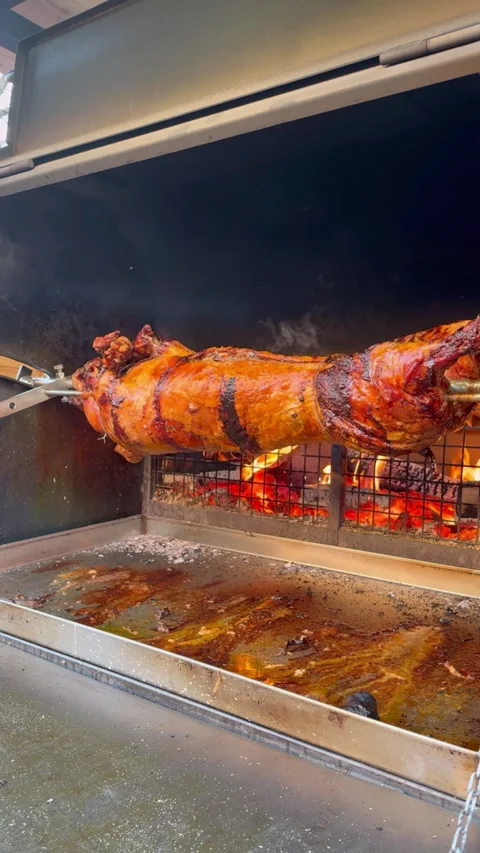 Roasting pig on a spit turns slowly roasting it. BBQ. Stock Footage 294184080