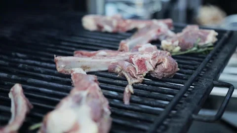Roasting pork ribs on a grill grate in a barbecue oven, slow motion, close-up Video stock 314887476
