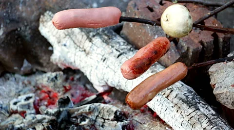 Roasting sausages over a fire Stock Footage 49733335