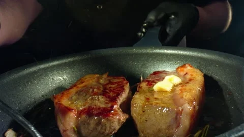 Roasting steaks on frying pan at kitchen, closeup view of cooking process. Shot Stock Footage 137318231