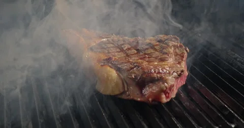 Roasting tomahawk steak on barbecue grid in smoke. Grilling BBQ meat. Juicy beef Stock Footage 271626627