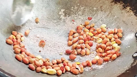Roasting whole peanuts with salt in an iron wok action shot. Stock Footage 342401277
