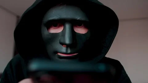 Robber in black mask using smartphone. Concept of hacking, scamming and phishing Stock Footage 329886079