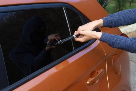 The robber breaks the car window to get inside Stock Photos
