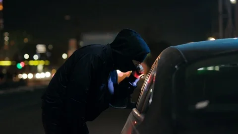 Robber man shines a flashlight in a car stealing at night crime male thief Vídeos de archivo 110888465