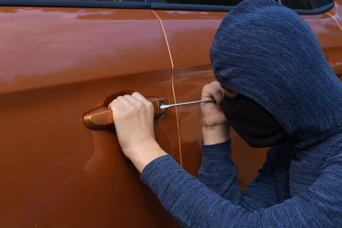 A robbery is breaking the law, hacks the lock on the car to get inside Stock Photos