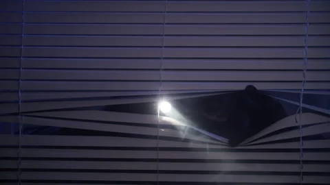 Robbery, man in balaclava shines flashlight through blinds at night looking for Stock Footage 305929947