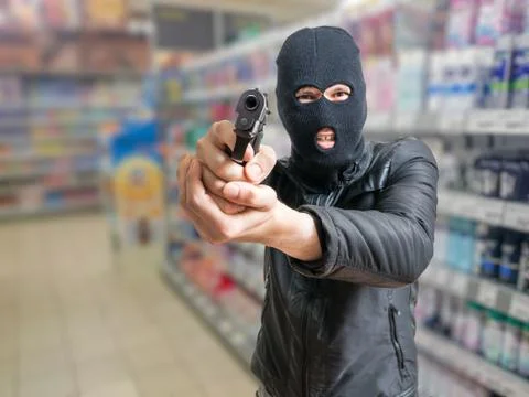 Robbery in store. Robber is aiming and threatening with gun in shop. 스톡 사진