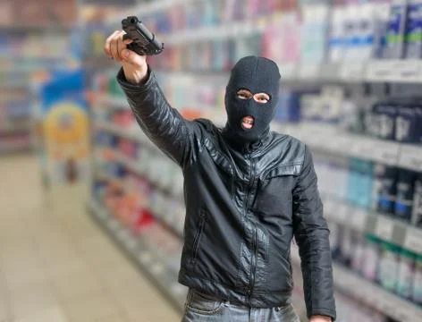 Robbery in store. Robber is threatening and aiming with pistol in shop. 스톡 사진