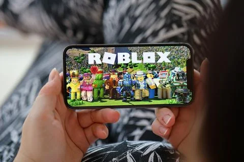 Roblox mobile iOS game on iPhone 15 smartphone screen in female hands during Fotos de archivo