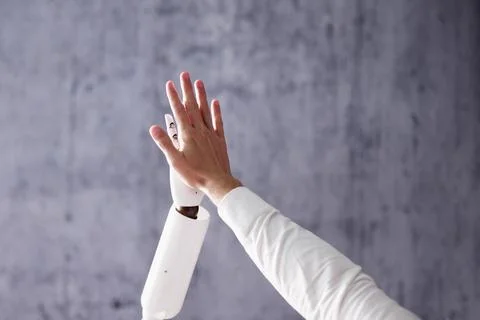 Robot And Man Giving High Five Against Gray Stock Photos